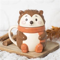 Squirrel-shaped mug with a scarf on a wooden board with snow and cinnamon sticks in the background