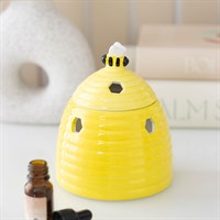 Yellow bee-shaped diffuser on a white surface with a bottle of essential oil.