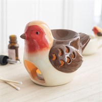 Ceramic bird-shaped candle holder on a wooden surface with a blurred background