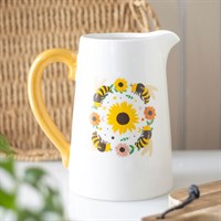 White pitcher with yellow handle featuring sunflower and bee design on a neutral background
